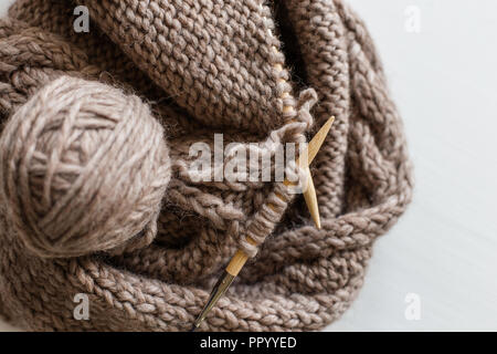 Beige knitting wool and knitting needles on white wooden background. Knitting as a hobby. Accessories for knitting. Stock Photo