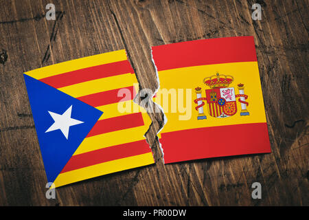 the Estelada, the Catalan pro-independence flag, and the flag of Spain, broken on a rustic wooden surface Stock Photo