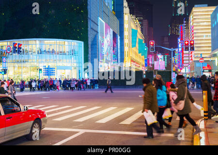 People walking on crossroad at shopping Shanghai street illuminated in the evening, China Stock Photo