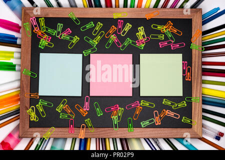 Colorful sticky notes on chalkboard with pencils on background, blank copy space Stock Photo