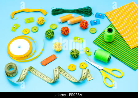 Cloth cotton shredders scissors thread pins centimeter measuring tape chalk buttons for sewing on a blue background Stock Photo