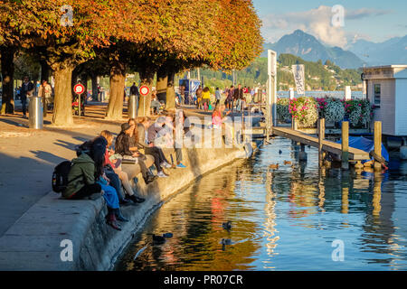 Lucerne, Switzerland – September 24, 2015: People are enjoying the setting sun on a late September day at the shores of Lake Lucerne Stock Photo