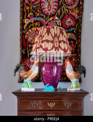 Tapestry wall hanging and lamp with cockerel statues Stock Photo