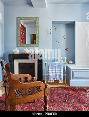 Carved wooden chair in light blue bathroom with seashells Stock Photo
