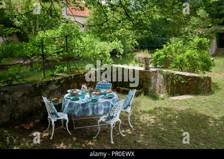 Circular table and chairs in garden on riverbank Stock Photo