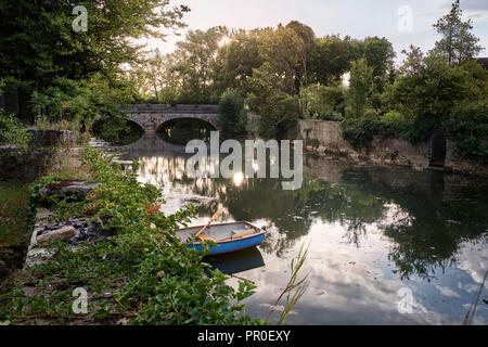 Rowing boat on river with arched stone bridge Stock Photo