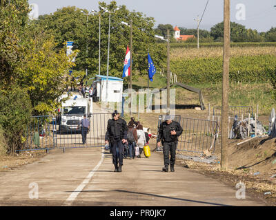 BERKASOVO, SERBIA - OCTOBER 3, 2015: Croatian policemen walking in front of a group of Refugees on the Croatian border crossing on the Croatia Serbia  Stock Photo