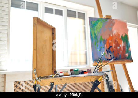 https://l450v.alamy.com/450v/pr0kjb/close-up-of-drawing-instruments-and-tools-artist-watercolors-brushes-and-easel-with-abstract-picture-on-background-against-big-window-at-studio-artist-workspace-in-painter-studio-concept-of-hobby-pr0kjb.jpg