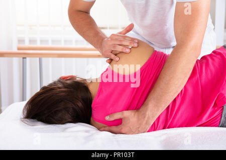 Close-up Of A Male Therapist's Hand Giving Shoulder Massage To Female Patient Stock Photo