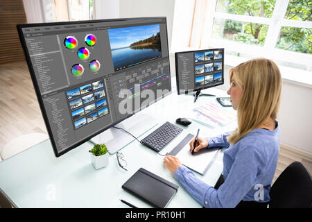 Female Editor Using Graphic Tablet While Editing Video On Computer Stock Photo