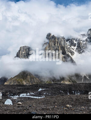 Jagged peaks from Biarchedi group of mountains appear behind clouds, Baltoro Galcier, Karakoram, Pakistan Stock Photo