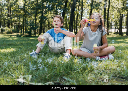 adorable children blowing soap bubbles in park Stock Photo