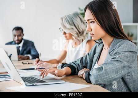 side view of multiethnic businesspeople working at table in office Stock Photo