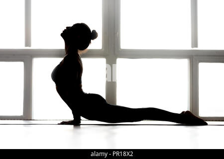 Young sporty yogi woman practicing yoga, doing upward facing dog Stock Photo