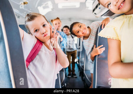 group of happy schoolchildren riding on school bus and looking at camera Stock Photo