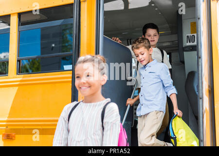 adorable scholars going out of school bus Stock Photo