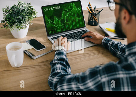 cropped shot of man in plaid shirt using laptop with online trade graph on screen Stock Photo