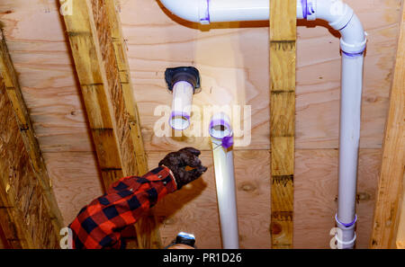 Plumbing building contractor installing plastic drain pipe in the for a luxury custom house Stock Photo