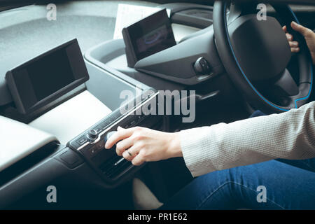 Businesswoman using music system while driving car Stock Photo