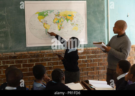 Schoolboy explaining about world map in classroom Stock Photo