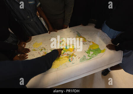 Schoolkids looking at world map in classroom Stock Photo