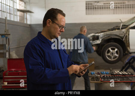 Male mechanic using digital tablet in garage Stock Photo