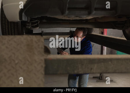Mechanic using digital tablet while servicing a car Stock Photo