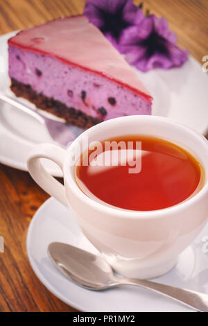 Cup of fresh hot tea with delicious piece of blueberry cake on the wooden table Stock Photo