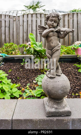 Stone statue of a young boy holding a bird bath in a country garden,  Lancashire UK. September 2018 Stock Photo - Alamy