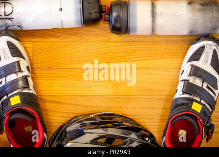 A wooden background with a set of cycling gear consisting of two water bottles, a pair of shoes and a helmet. Stock Photo