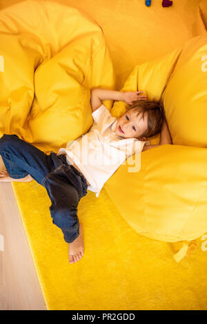 high angle view of adorable boy lying on bean bag chair in kindergarten Stock Photo