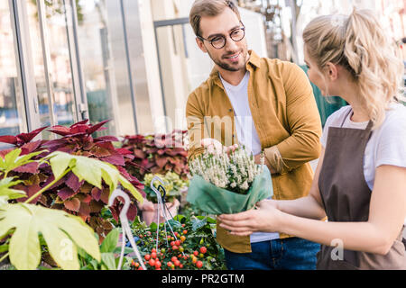 florist helping customer choosing potted plant at flower shop Stock Photo
