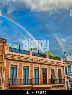 One rainbow and a partial other one over the rooftops of apartments in Valencia, Spain after a storm Stock Photo