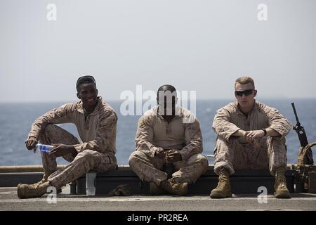 GULF OF ADEN (July 25, 2017) U.S. Marine Corps Sgt. Isaiah Woods, left, Sgt. Kristopher Brown, center, and Sgt. Seth Mullins, right, all with 3rd Battalion, 6th Marines, stand by during a combat marksmanship program shoot on the flight deck of USS Carter Hall (LSD 50), Gulf of Aden, July 25, 2017. The 24th Marine Expeditionary Unit is currently deployed to the U.S. 5th Fleet area of operations in support of maritime security operations designed to reassure allies and partners and preserve the freedom of navigation and the free flow of commerce in the region. Stock Photo