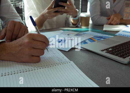 Executive writing on diary on table in office Stock Photo