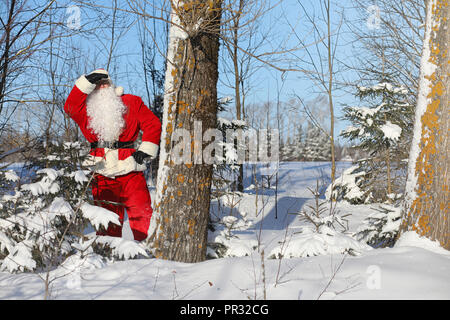 Santa Claus comes with gifts from the outside. Santa in a red su Stock Photo