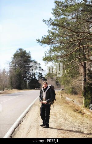 A young man is hitchhiking around the country. The man is trying Stock Photo