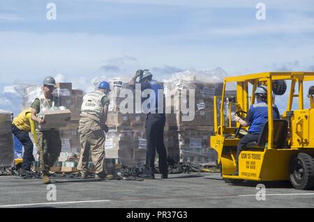 PACIFIC OCEAN (July 29, 2017) Sailors and Marines aboard the amphibious assault ship USS America (LHA 6) move cargo from the ship’s flight deck elevator into storerooms during a replenishment-at-sea with the dry cargo/ammunition ship USNS Wally Schirra (T-AKE 8). America, part of the America Amphibious Ready Group, with embarked 15th Marine Expeditionary Unit, is operating in the Indo-Asia Pacific region to strengthen partnerships and serve as a ready-response force for any type of contingency. Stock Photo