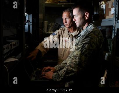 Master Sgt. Kyle Tschida, a Joint Interface Control cell watch officer with the 609th Air Operations Center, right, and Lt. Col. Terry Brennan, deputy U.S. Air Forces Central Command JIC officer, review datalink software changes July 21, 2017, at the Combined Air Operations Center on Al Udeid Air Base, Qatar. Brennan led a team that re-engineered theater data link architecture and provided reliable connectivity and responsive data link message traffic for the warfighter. Stock Photo