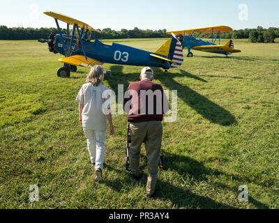 Al Tucker Jr. and his daughter , Sue Tucker Brander, walk towards the PT-17 Stearman biplane owned by First Sgt. David Brown, U.S. Air Force Reserve, before Tucker and Brown took to the air following the Flying Circus Airshow in Bealeton, Va., Jul. 30, 2017. Brander introduced her father to Brown, whose PT-17 is the same model in which Tucker trained at West Point in 1942 before going on to fly P-38 fighter aircraft over Europe with the U.S. Army Air Corps 434th Fighter Squadron during WWII with his friend, then Lt., Robin Olds. Stock Photo