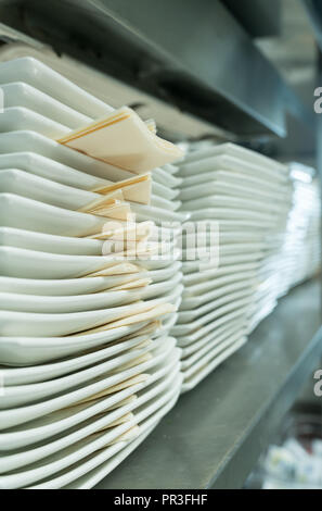 endless row of ceramic dinner plates neatly stacked on a metal shelf Stock Photo