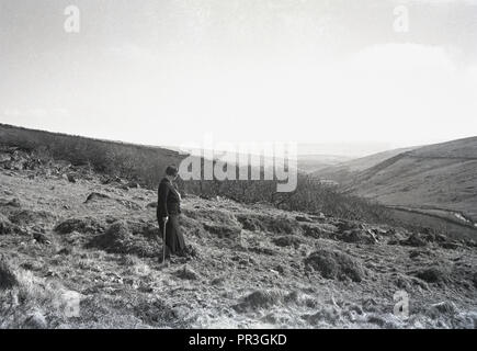 1930s, historical, a lady walker with stick standing near Longaford Tor at Dartmoor national park in Devon, England, UK, a wild natural moorland that contains many rock formations known as tors. Stock Photo