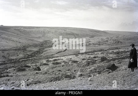 1930s, historical, a lady walker standing looking over Dartmoor national park in Devon, England, UK, a natural wild open moorland that contains many granite outcrops known as tors. Stock Photo