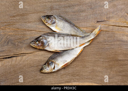 Three dried fishes on wooden background. High resolution photo. Stock Photo