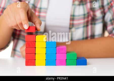 Concept of building success foundation. Women hand put colorful wooden blocks in the shape of a staircase Stock Photo