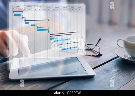 Project manager updating progress and deliverables milestones schedule on gantt chart planning with digital tablet computer, professional planner in o Stock Photo