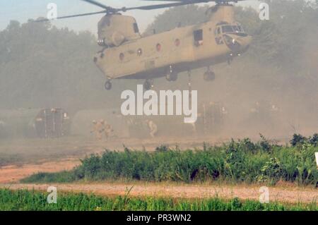 Three U.S. Army Soldiers from a Multi-Role Bridge Company run away from the roto wash of a CH-47 Chinook of Company B, 7th (General Support Aviation) Battalion, 158th Aviation Regiment, 244th Aviation Brigade, Army Reserve Aviation Command as it begins to lift an Improved Ribbon Bridge (IRB) Bay Section during River Assault 2017 on Fort Chaffee Manuever Training Center, July 26, 2017. The Chinook dropped off the bay in the Arkansas River in order for the IRB to be built across the river, the culminating event of River Assault. Operation River Assault is one of the key training events that demo Stock Photo