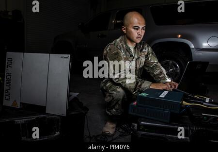 U.S. Air Force Staff Sgt. Junbryan Samson, a cyber network technician assigned to the U.S. Air Forces Central Command communications division at the Combined Air Operations Center, tests a communications fly-away kit July 31, 2017, at Al Udeid Air Base, Qatar. Samson ensures the CFK is maintained and ready to deploy at a moments notice to bases around the AFCENT region to create command and control network connections. Stock Photo