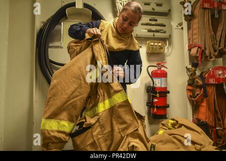 PACIFIC OCEAN (July 29, 2017) Damage Controlman 3rd Class Carla Olivares, a native of Charlotte, North Carolina, assigned to the Engineering department aboard the amphibious dock landing ship USS Pearl Harbor (LSD 52), inspects a firefighting ensemble during a general quarters drill. Pearl Harbor, part of the America Amphibious Ready Group, with embarked 15th Marine Expeditionary Unit, is operating in the Indo-Asia Pacific region to strengthen partnerships and serve as a ready-response force for any type of contingency. Stock Photo