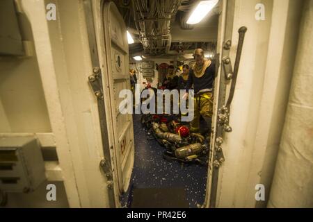 PACIFIC OCEAN (July 29, 2017) Sailors assigned to the amphibious dock landing ship USS Pearl Harbor (LSD 52) don their firefighting ensemble during a general quarters drill. Pearl Harbor, part of the America Amphibious Ready Group, with embarked 15th Marine Expeditionary Unit, is operating in the Indo-Asia Pacific region to strengthen partnerships and serve as a ready-response force for any type of contingency. Stock Photo